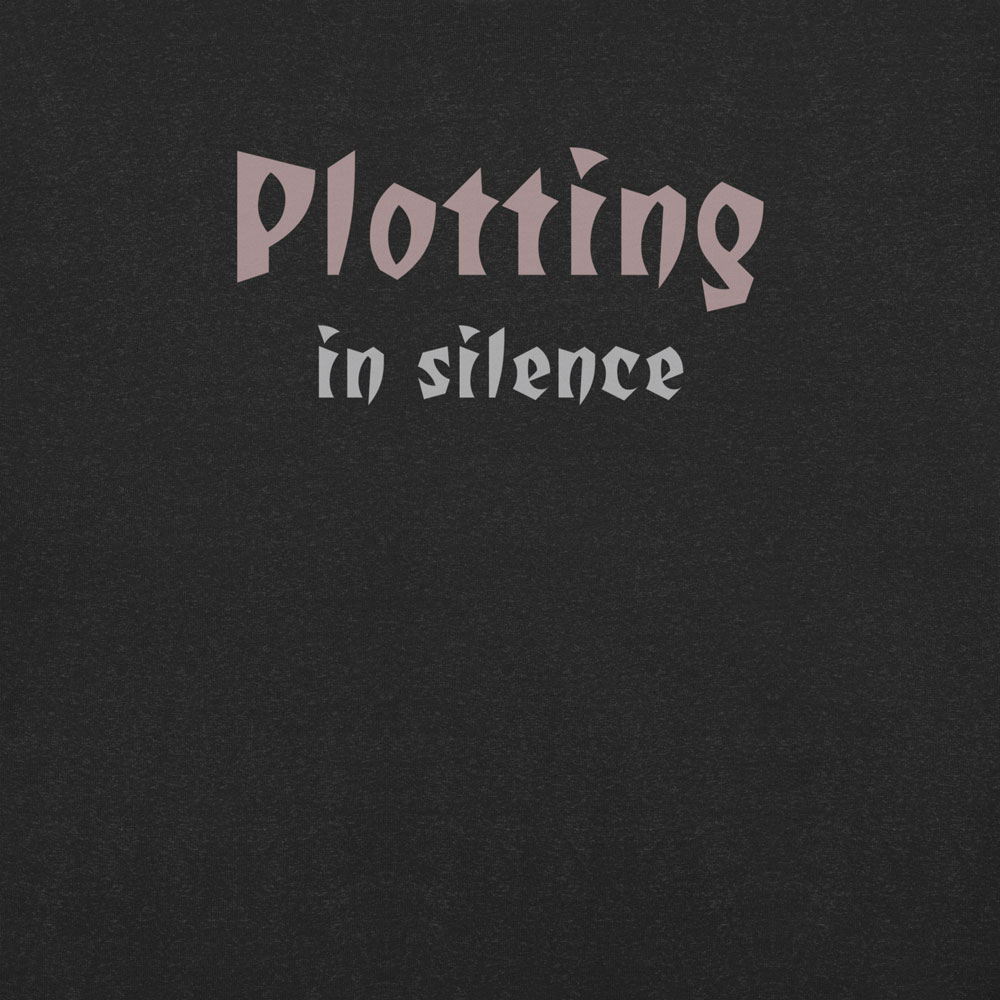 Gothic-style text design reading “Plotting in Silence” in bold, moody font on a black t-shirt.